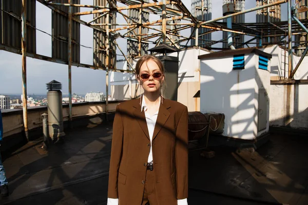 Stylish young model in sunglasses posing on rooftop — Stock Photo