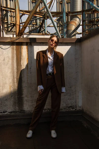 Full length of stylish young model in brown suit posing on rooftop — Stock Photo