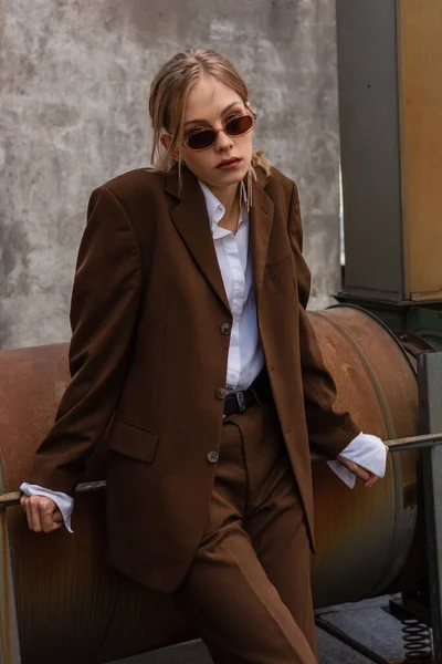 Young blonde model in sunglasses and trendy suit posing on rooftop — Stock Photo