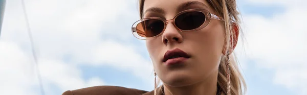 Junge Frau mit Sonnenbrille posiert vor blauem Himmel, Banner — Stockfoto