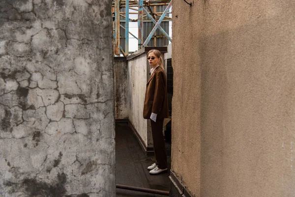 Longitud completa de la elegante modelo rubia posando cerca de la construcción en la azotea - foto de stock