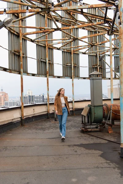 По всей длине молодой женщины в джинсах и модных кроссовках, идущей по крыше — стоковое фото