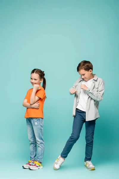 Shy girl standing near boy dancing on blue — Stock Photo