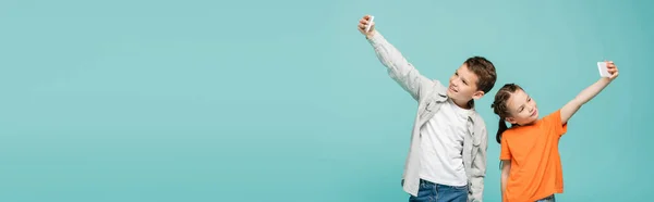 Crianças sorrindo tomando selfie em celulares isolados em azul, banner — Fotografia de Stock