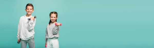 Niños felices en ropa deportiva trabajando con pesas aisladas en azul, pancarta - foto de stock