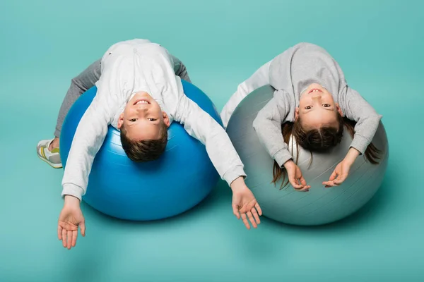 Happy children in sportswear working out on fitness balls on blue — Stock Photo