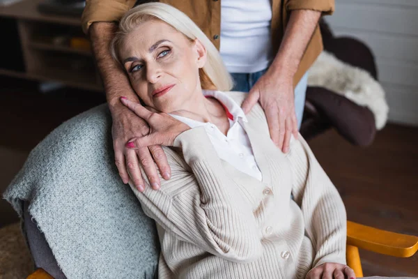 Senior mulher tocando mão do marido enquanto sentado na poltrona — Fotografia de Stock