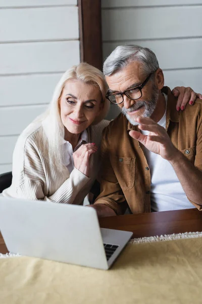 Senior woman hugging husband during video call on laptop — Stock Photo