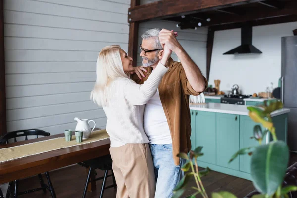 Вид збоку весела старша жінка танцює з чоловіком вдома — стокове фото