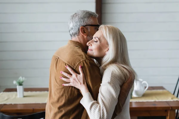 Seitenansicht einer Seniorin, die ihren Mann zu Hause umarmt — Stockfoto