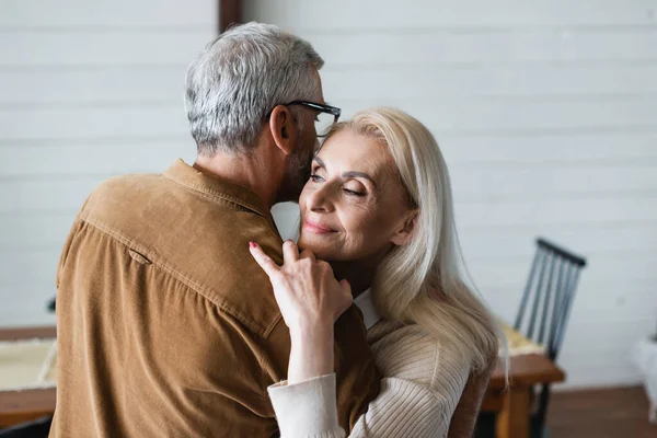 Smiling woman embracing husband in eyeglasses — Stock Photo