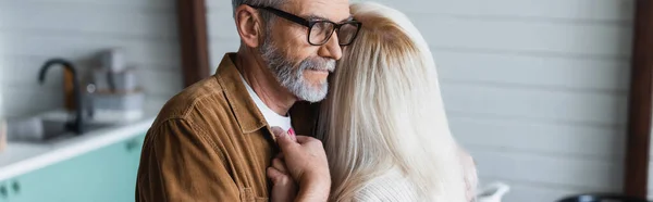 Uomo anziano con gli occhiali che tiene per mano la moglie, striscione — Foto stock