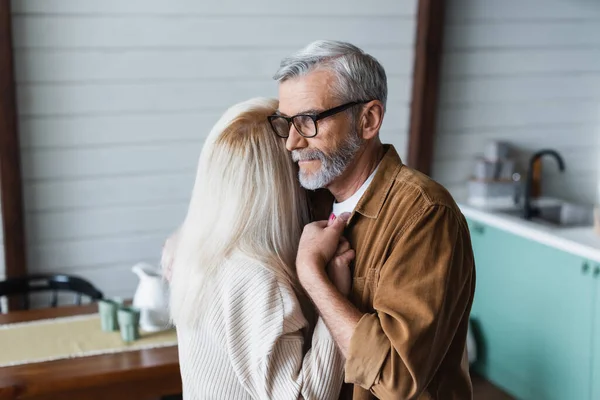 Старший чоловік в окулярах тримає руку дружини вдома — стокове фото