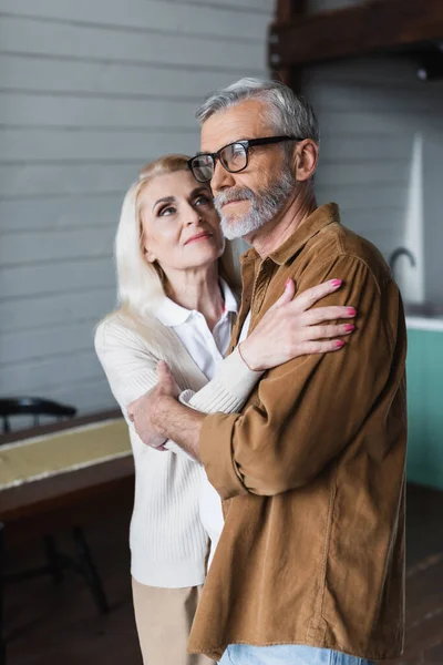 Donna che abbraccia e guarda il marito anziano a casa — Foto stock