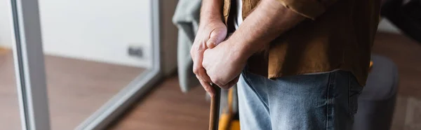 Cropped view of senior man with crutch standing at home, banner — Stock Photo