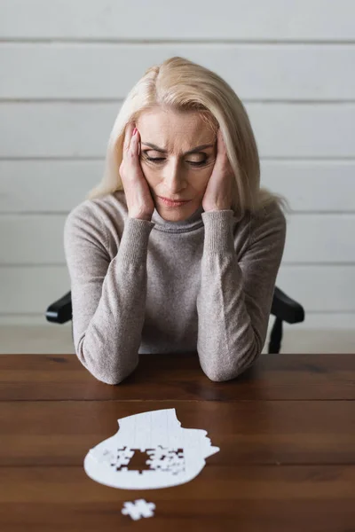 Mujer mayor molesto con Alzheimer mirando rompecabezas en primer plano borrosa - foto de stock