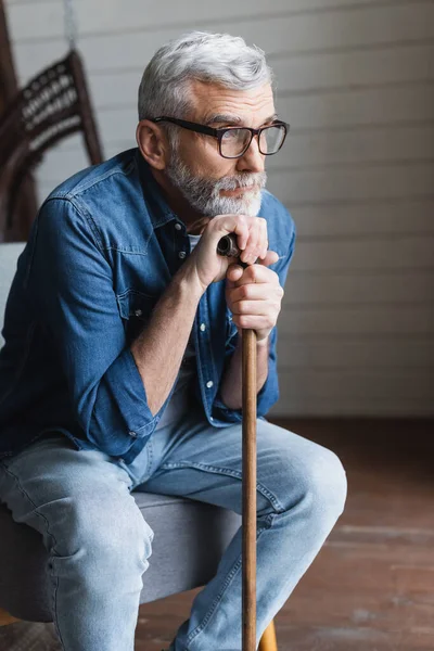 Homme âgé avec béquille regardant loin à la maison — Photo de stock