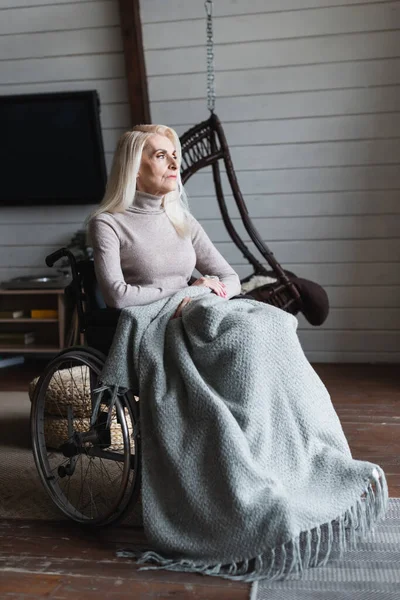 Ältere Frau sitzt zu Hause im Sessel mit Decke — Stockfoto