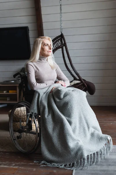 Elderly woman sitting in armchair with blanket at home — Stock Photo