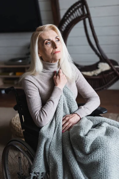 Femme seule tenant une couverture sur un fauteuil à la maison — Photo de stock