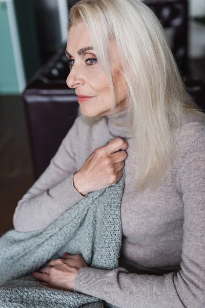 Femme âgée seule tenant une couverture à la maison — Photo de stock