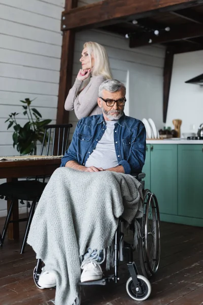 Triste handicapé en fauteuil roulant regardant loin près de sa femme à la maison — Photo de stock