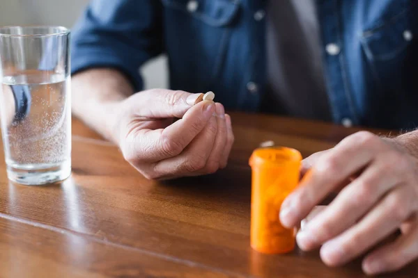 Ausgeschnittene Ansicht eines älteren Mannes mit Tablette in der Nähe von Glas und Glas Wasser — Stockfoto