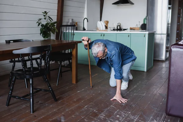 Homem idoso com muleta caindo no chão em casa — Fotografia de Stock