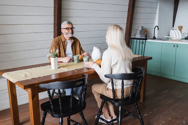 Старший мужчина смотрит на жену за завтраком дома — стоковое фото
