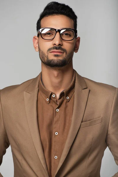 Мусульманський бізнесмен у окулярах дивиться на камеру, ізольовану на сірому — стокове фото