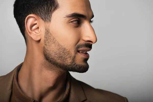 Vue latérale d'un homme d'affaires arabe souriant regardant loin sur fond gris — Photo de stock