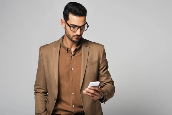 Hombre de negocios árabe usando teléfono inteligente aislado en gris - foto de stock