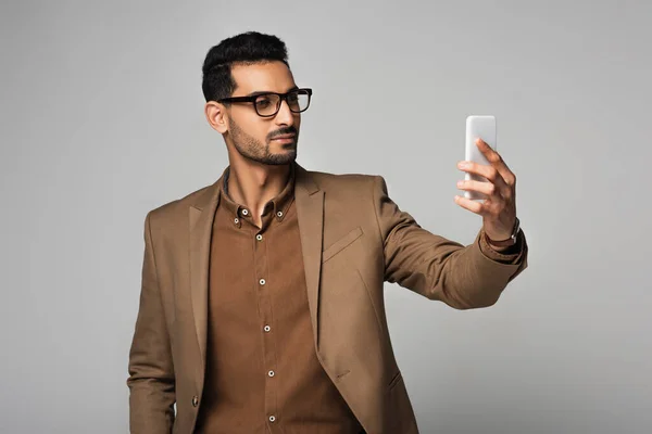 Мусульманский бизнесмен использует мобильный телефон, изолированный на сером — стоковое фото