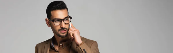 Muslim businessman talking on smartphone and looking away isolated on grey, banner — Stock Photo