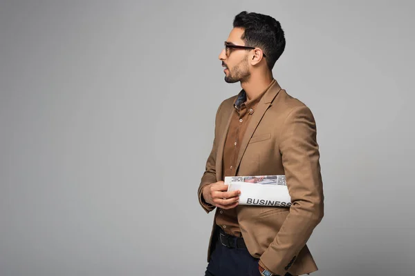 Seitenansicht eines muslimischen Geschäftsmannes, der Zeitung isoliert auf grau hält — Stockfoto
