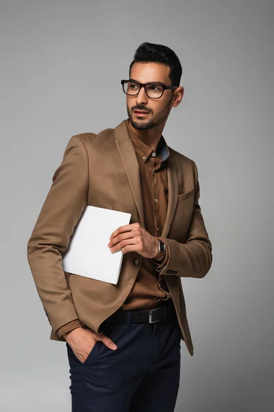 Young muslim businessman in eyeglasses holding papers isolated on grey — Stock Photo