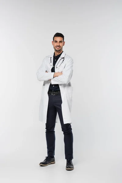 Smiling arabian doctor standing with crossed arms on grey background — Stock Photo