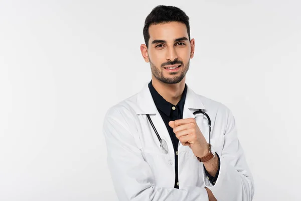 Médico árabe positivo de capa blanca mirando una cámara aislada en gris - foto de stock
