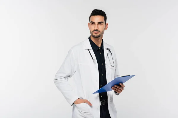 Médico musulmán con portapapeles mirando hacia otro lado aislado en gris - foto de stock
