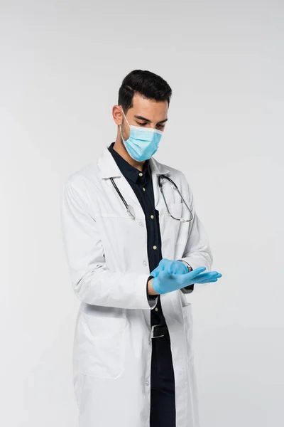 Médico musulmán en máscara médica con guantes de látex aislados en gris - foto de stock