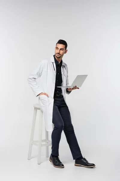 Muslim doctor with laptop looking away on grey background — Stock Photo