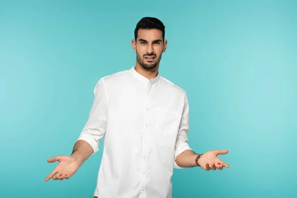 Confused arabian man pointing with hands isolated on blue — Stock Photo