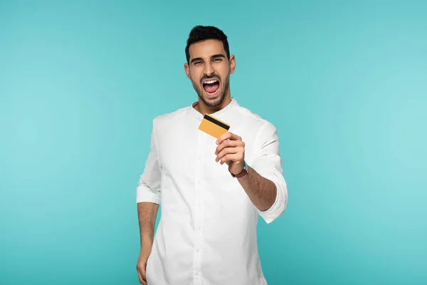 Homem árabe animado mostrando cartão de crédito isolado em azul — Fotografia de Stock
