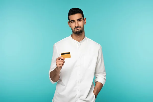 Homme musulman mécontent avec carte de crédit regardant la caméra isolée sur bleu — Photo de stock
