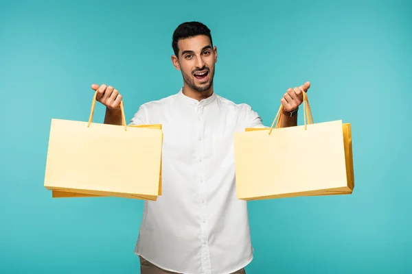 Happy muslim customer holding shopping bags isolated on blue — Stock Photo