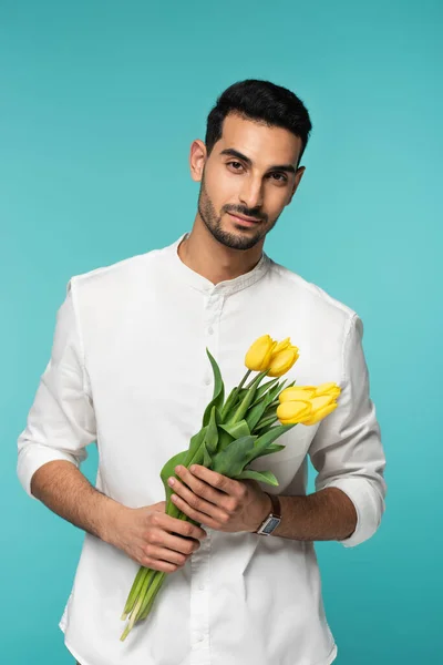 Araber mit gelben Blumen blickt vereinzelt in die Kamera auf blauem Grund — Stockfoto