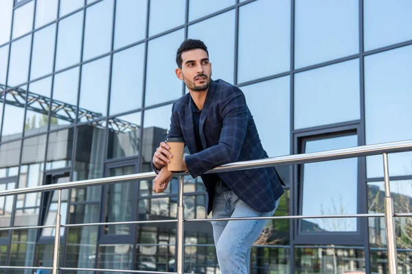 Gut aussehender muslimischer Geschäftsmann hält Kaffee in der Nähe von Gebäuden — Stockfoto