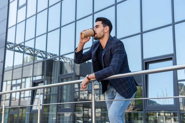 Uomo d'affari musulmano bere caffè per andare vicino ringhiera all'aperto — Foto stock