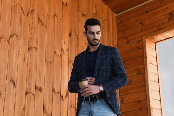 Hombre de negocios musulmán con café para ir mirando reloj de pulsera al aire libre - foto de stock
