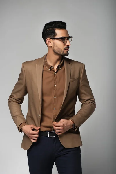 Vista lateral do gerente muçulmano em óculos ajustando jaqueta isolada em cinza — Fotografia de Stock